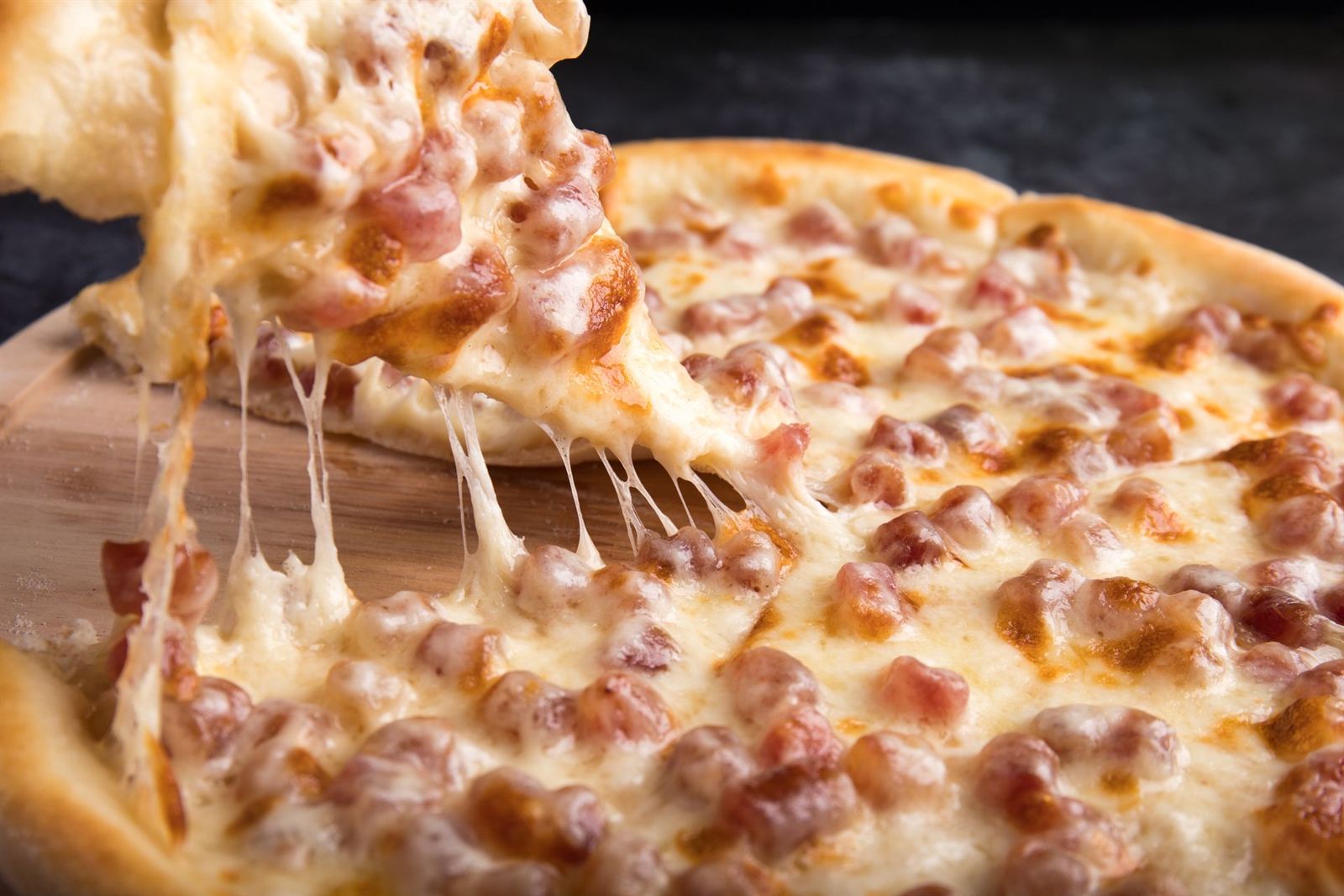 Part de pizza dont le fromage file, photo d'illustration