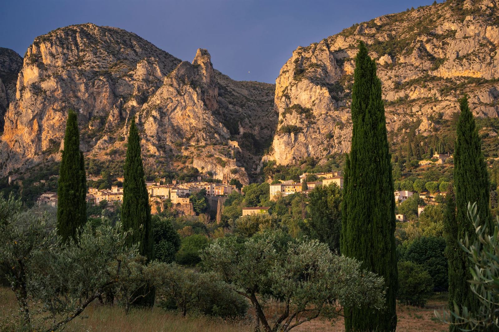 Falaises, cyprès et village de pierre de Haute-Provence à l'heure dorée, photo d'illustration